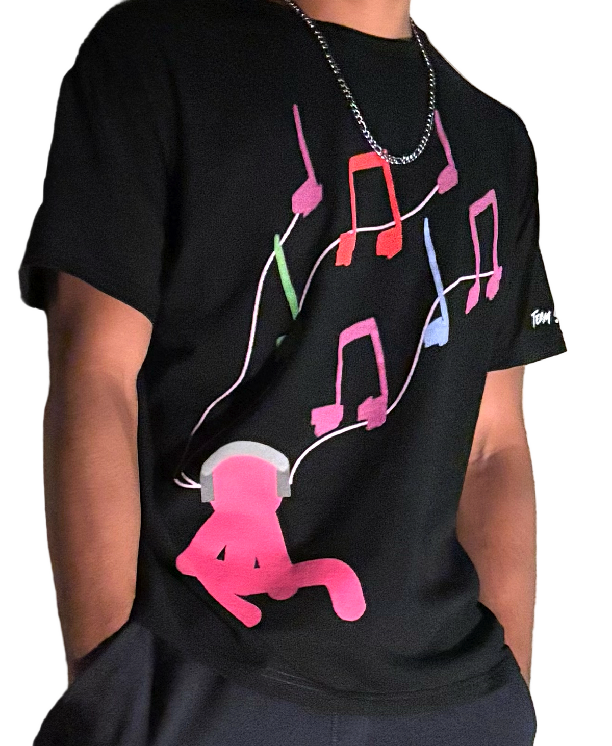Person wearing a black t-shirt with colorful music note design and pink cartoon character.